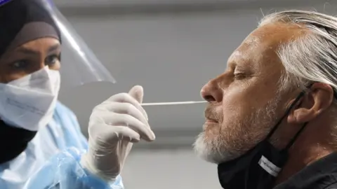 Reuters A traveller receives a test for the coronavirus disease (COVID-19) at a pre-departure testing facility, as countries react to the new coronavirus Omicron variant, outside the international terminal at Sydney Airport in Sydney, Australia, November 29, 2021