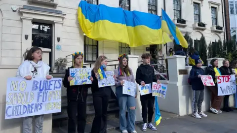 Pupils hold placards outside the Ukrainian school