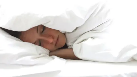 Getty Images Woman hiding under the duvet