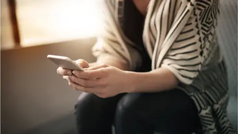 Getty Images Woman holding a phone