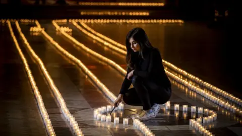 PA Media Holly Wilson, whose grandmother Ada Wilson passed away during the pandemic, stands in Belfast Cathedral before a remembrance service in partnership with Marie Curie for their National Day of Reflection, to mark the 2,100 people who have lost their lives to Covid in Northern Ireland