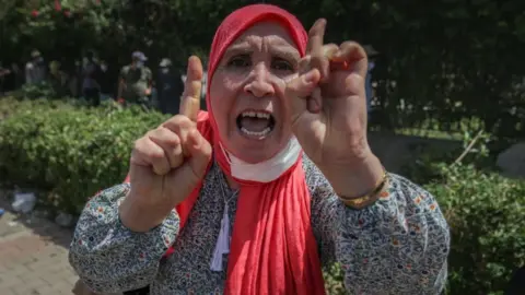 AFP A female supporter of the Islamist party Ennahdha gestures as she chants slogans during a sit-in protest led by the Tunisian Parliament Speaker Rached Ghannouchi, in front of the building of the Tunisian parliament in Bardo, in the capital Tunis, Tunisia, on July 26, 2021