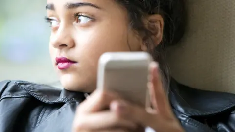 Getty Images young girl early teens playing on her phone and texting