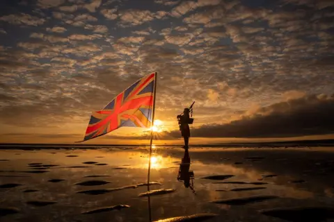 Jane Barlow/PA Media Scotland's National Piper Louise Marshall playing a lament to the fallen at dawn on Portobello Beach in Edinburgh, overlooking the Firth of Forth on the 80th anniversary of VE Day