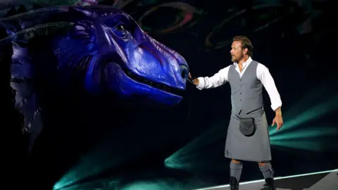 PA Media Kilted Sam Heughan with a giant model of the Loch Ness Monster
