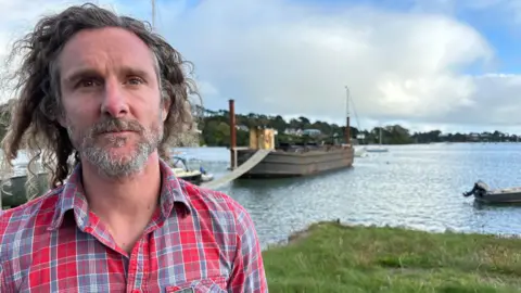 LeeTrewhela/LDRS Dean Richards pictured in front of his barge, moored on his own land on the foreshore at Point Quay near Truro