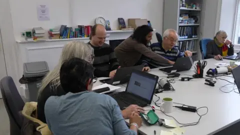 A group of men and women looking at computer screens in a classroom 