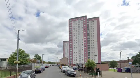 cars parked in the street outside a group of high-rise flats