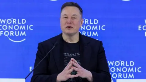 Reuters Elon Musk, dressed in black, speaks at the World Economic Forum conference in Davos, Switzerland
