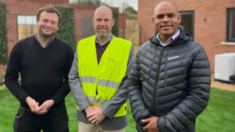 BBC Three men standing in front of a new housing development
