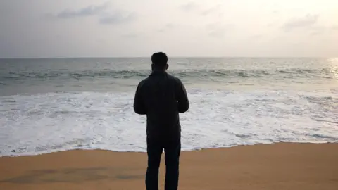 Vishnu Vardhan Het beeld toont de achterkant van een man in silhouet die staart naar de enorme uitgestrektheid van de Indische Oceaan in Kerala, India. 