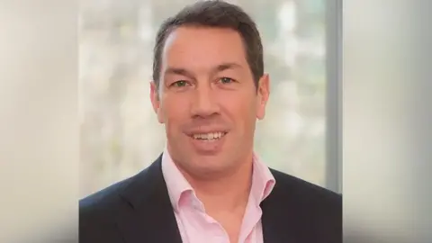 Northumbria Police/PA Wire Tom Voyce in a formal photograph smiling at the camera and wearing a blue suit and pink, open-necked shirt.