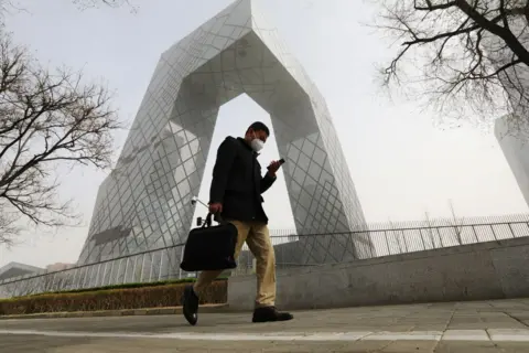 Getty images A man walks past the China Central Television (CCTV) headquarters building during a sandstorm on March 22, 2023 in Beijing,