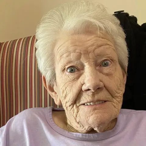 Family handout A woman in her 80s with short white hair and wearing a lilac top smiles at the camera.