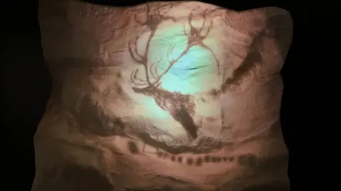 What looks like a cave drawing of a deer or elk on a piece of stone with a light shone on it