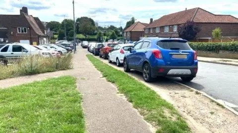 LDRS Several cars parked on a residential street pavement.
