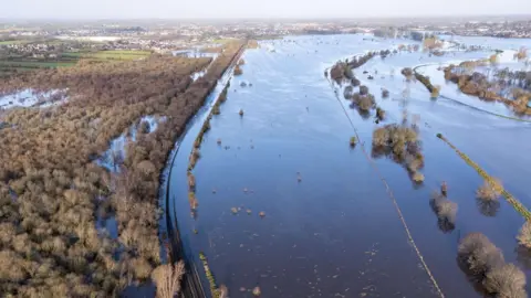 Matt Crockett An aerial view of land around Brackagh bog, south of Portadown, on Wednesday morning. Fields and woodland appear to be under water after nearby waterways flooded. The train track which skirts around the wooded area is partially submerged. 