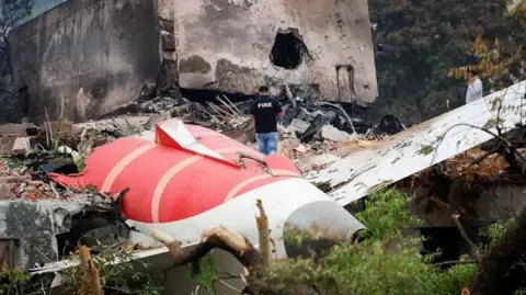A fire officer stands next to the tail section of the crashed Air India Boeing 787-8 Dreamliner aircraft, in Ahmedabad, India.