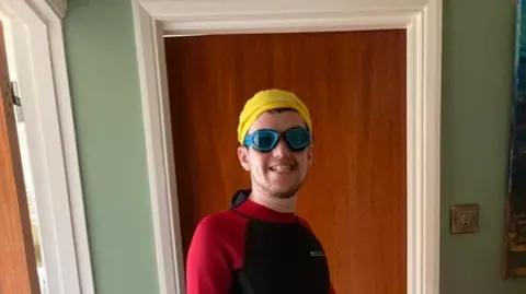 Paula Maguire A man smiles wearing a red and black wet suit 