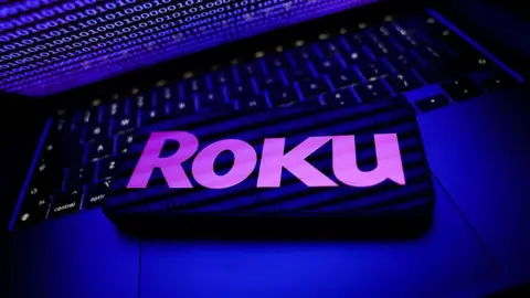 Binary code displayed on a laptop screen and Roku logo displayed on a phone screen