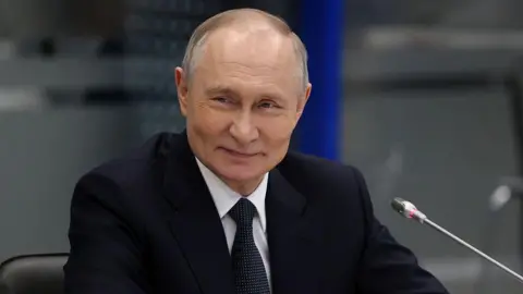 Russian President Vladimir Putin smiles duting a meetng, while visiting a military base of nuclear submarines, March 26, 2025, in Murmansk, Russia