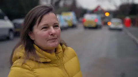 Magda speaks to the BBC outside. She is wearing a yellow coat. 