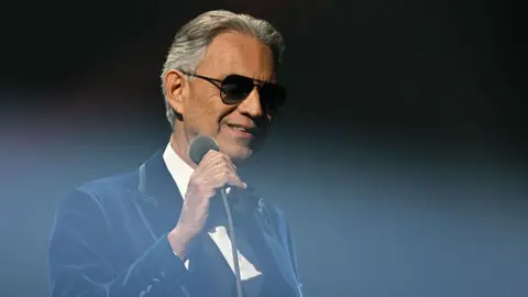 Andrea Bocelli wearing sunglasses and a balck tuxedo