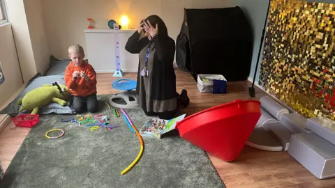 An adult and a child in a small room with toys