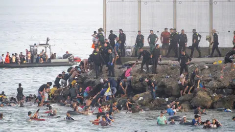 Migrants swimming to shore off Ceuta. 