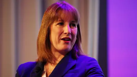 Getty Images Rachel Reeves, a woman in her 40s with medium-length brown hair, is wearing a blue suit.