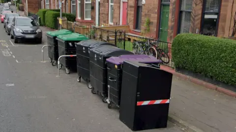 Google A line of communal bins on a residential street.