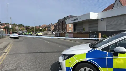 Police tape blocking the road near a supermarket