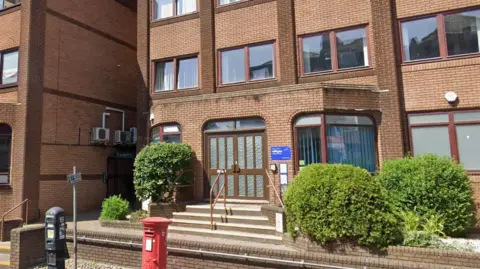 Google Brick offices of We Are With You in Bournemouth. There is a low wall surrounding the building and steps leading up to the brown double doors