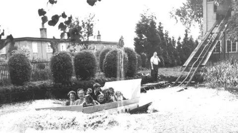 Wicksteed Park Black and white photo of water chute, showing a group of mainly children in a boat at the bottom of the chute