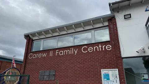 The exterior of the Carew Family Centre in east Belfast. It has 'Carew Family Centre' written in large, silver letters on the side of the red brick, two-storey building.