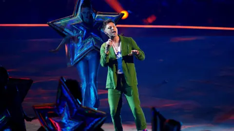 PA Media Callum Beattie in a green suit singing on stage