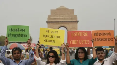 Getty Images NEW DELHI, INDIA - 13 MEI: Aktivis Purush Aayog memegang plakat untuk menggelar protes menuntut hukuman bagi penuduh kasus pelecehan seksual terhadap Ketua Hakim India Ranjan Gogoi, di Gerbang India, pada 13 Mei 2019 di New Delhi , India. Para pengunjuk rasa mengatakan ada kebutuhan untuk mengubah Pasal 498A KUHP India untuk mencegah penyalahgunaannya. Ketentuan tersebut mengatur tentang kekejaman terhadap perempuan, termasuk pelecehan terkait mahar, yang dilakukan oleh suami dan kerabat suami. (Foto oleh Vipin Kumar/Hindustan Times melalui Getty Images)