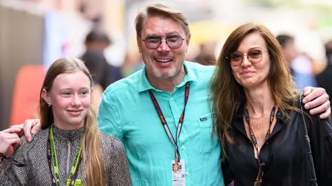 Getty Images Ella Hakkinen - wearing a grey pattern top, on the left of her father Mika Hakkinen, who is wearing a blue shirt and sunglasses, standing next to wife Marketa Remesova, wearing a black top and sunglasses.