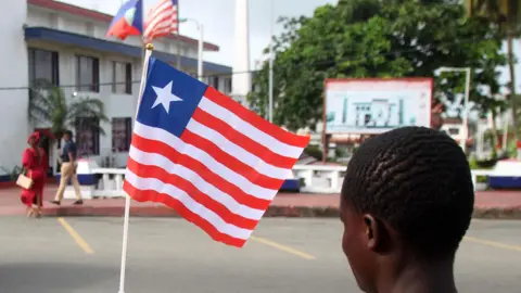 A back view of person holding a small Liberian flag on a street in Monrovia