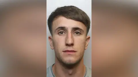 West Yorkshire Police A police mugshot of Kai Helliwell. He has short brown hair and brown eyes. He is wearing a grey jumper