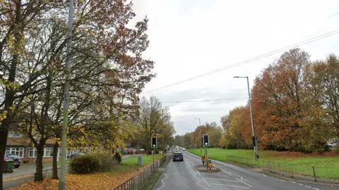 Cannock Road going out of the city. Trees are on both sides of the road with houses on the left.