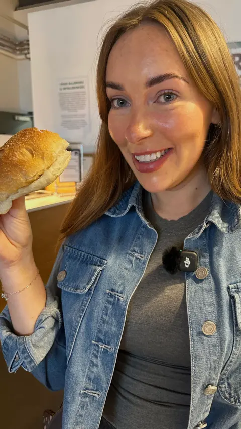 A young woman holding a roll and smiling at the camera