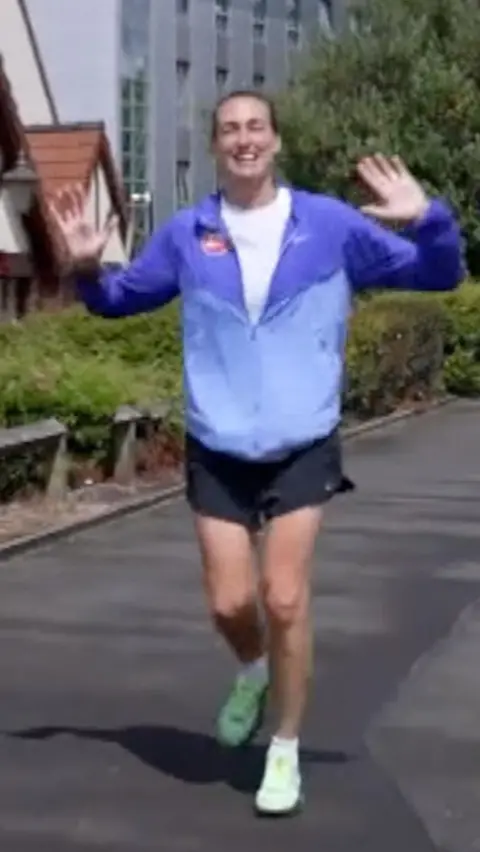 Jill Scott wearing blue jacket with black shorts and green shoes