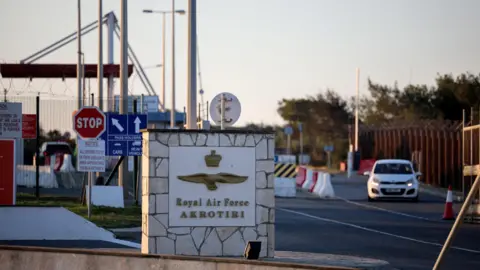 Reuters A landscape image of the entrance to RAF Akrotiri - a sign reads 'Royal Air Force Akrotiri' and a white car is in the background