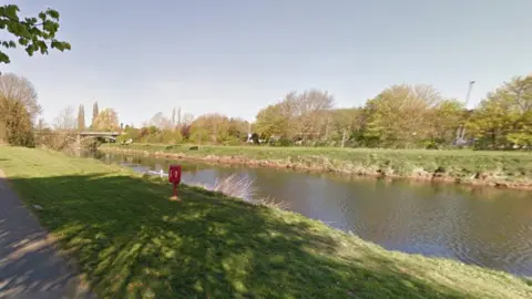 Google Generic image of the River Wye in Hereford, with grass on both sides of the river. There are several trees on the opposite side of the river to the camera and a bridge in the distance going across the river. 
