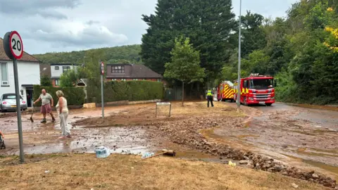 A fire engine can be seen at a street, which is covered in mud and stones. 