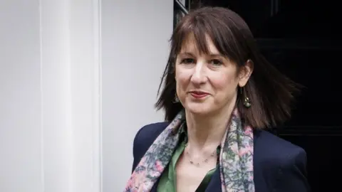 EPA Rachel Reeves emerging from Number 11 Downing Street, wearing a patterned scarf over a green shirt and dark blue jacket