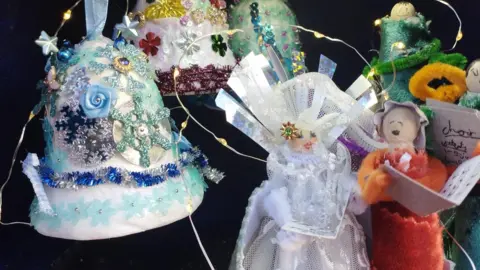 Quarry Chapel Church Inside of an advent calendar. There are three decorated bells and two human figures singing with one holding a book.