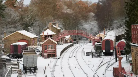 PA Media A railway station covered in snow.