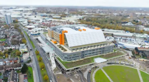 An aerial view of a large building with orange pillars and a grassy area surrounding it
